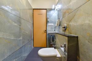 a bathroom with a toilet and a yellow door at FabHotel Prime Grand Unity, Changodar in Ahmedabad