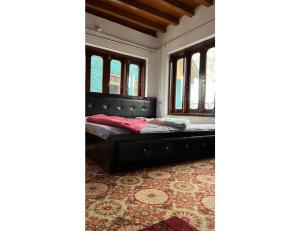 a black bed in a room with windows at Hotel Dayban Resort, Pahalgam in Pahalgām