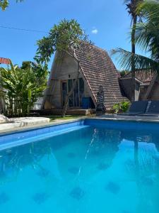 a house with a large swimming pool in front of it at Kuri Garden Cottage in Nusa Penida