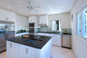 eine Küche mit weißen Schränken und einer schwarzen Arbeitsplatte in der Unterkunft Porters Villa by Blue Sky Luxury in Saint James