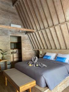 sypialnia z dużym łóżkiem i drewnianym sufitem w obiekcie Kuri Garden Cottage w mieście Nusa Penida