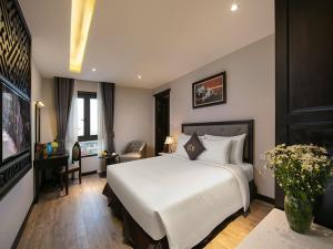 ein Schlafzimmer mit einem großen weißen Bett und einem TV in der Unterkunft Sen Grand Hotel & Spa managed by Sen Group in Hanoi