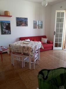 ein Wohnzimmer mit einem Tisch und einem roten Sofa in der Unterkunft Villetta Via Fregene in Marina di Ragusa