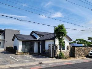 een wit huis met een stenen muur bij Doldamine Jeju in Jeju-stad