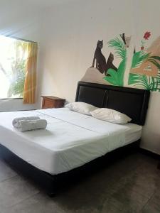 a bed in a bedroom with a black cat on the wall at Vico hotel in Nusa Dua