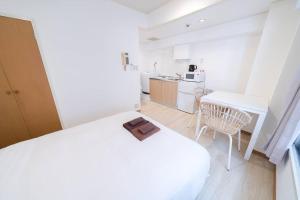 a white bedroom with a white bed and a table at Takadanobaba Address102 in Tokyo