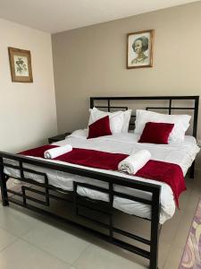 a large bed with red and white pillows on it at Imbasa House - Arusha in Arusha