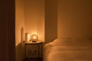 a room with a bed and a small table with a lamp at Takadanobaba Address102 in Tokyo