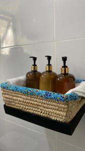 trois bouteilles de savon dans un panier en osier sur une étagère dans l'établissement Imbasa House - Arusha, à Arusha