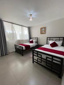 a bedroom with two beds and a window at Imbasa House - Arusha in Arusha