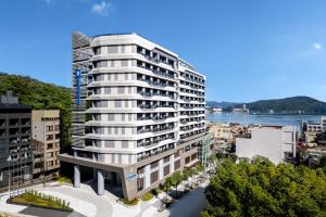 a tall white building with a river in the background at Wyndham Sun Moon Lake in Yuchi
