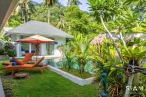 a garden with a chair and an umbrella and a pool at Villa Sumalee 3Br Private Pool in Koh Samui 