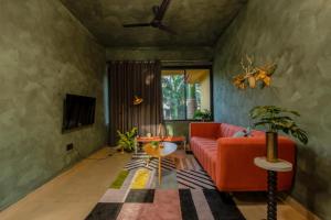 a living room with a red couch and a table at Mossy - Aesthetic 2BHK Apartment - Vagator, Goa By StayMonkey in Vagator