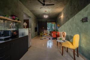 a kitchen with yellow chairs and a living room at Mossy - Aesthetic 2BHK Apartment - Vagator, Goa By StayMonkey in Vagator