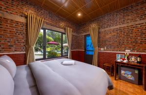 een slaapkamer met een groot wit bed en een bakstenen muur bij Trang An Spring Garden Homestay in Ninh Binh