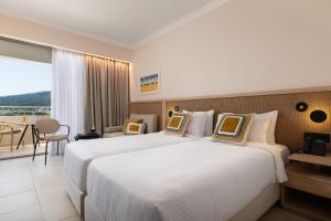 a hotel room with two beds and a balcony at Electra Palace Rhodes - Premium All Inclusive in Ialyssos