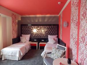 Habitación roja con 2 camas y silla en Simfonia Boutique Hotel, en Râmnicu Vâlcea