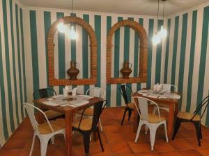 グアダルーペにあるHostal Altamira Guadalupeのダイニングルーム(テーブル2台、椅子、鏡2つ付)