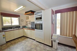 a large kitchen with white appliances and a window at Aquarius - Kalbarri, WA in Kalbarri