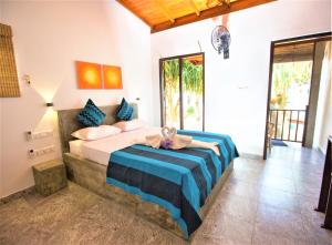 a bedroom with a large bed with blue and white sheets at Sea Shell Villa Hikkaduwa 2 Separate Cabanas Ocean Front Villa in Hikkaduwa