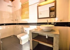 ein Badezimmer mit einem Waschbecken, einem WC und einem Spiegel in der Unterkunft Sea Shell Villa Hikkaduwa 2 Separate Cabanas Ocean Front Villa in Hikkaduwa