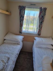 チャペル・セント・レオナルズにあるPg151 PALM GROVE THE GOLDEN PALM CHAPEL ST LEONARDSの窓のある小さな部屋にベッドが2つある +12枚の写真