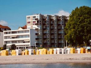 un gran edificio de apartamentos junto a una playa con sillas en Penthaus Horizont mit Meerblick, en Lübeck