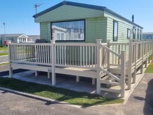 チャペル・セント・レオナルズにあるPg151 PALM GROVE THE GOLDEN PALM CHAPEL ST LEONARDSの緑家の前の大きな木製のベンチ