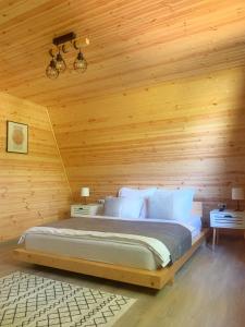 1 dormitorio con 1 cama en una pared de madera en Cabana A Vaideeni, en Vaideeni