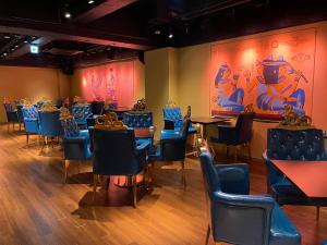 una sala da pranzo con sedie blu, tavoli e dipinti di Sauna & Cabin Thermae-yu Nishiazabu a Tokyo