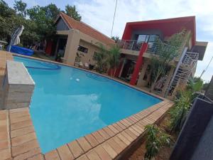 a large blue swimming pool in front of a house at Manasseh Guesthouse in Gaborone