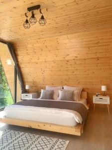 1 dormitorio con 1 cama grande en una pared de madera en Cabana A Vaideeni, en Vaideeni