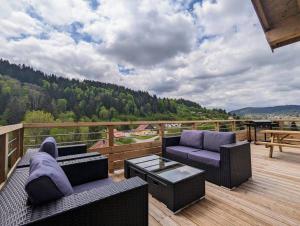 um pátio com 2 sofás e uma mesa num deque em Chalet Victorine, vue imprenable avec spa em Gérardmer