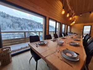 einen langen Holztisch in einem Zimmer mit einem großen Fenster in der Unterkunft Chalet Victorine, vue imprenable avec spa in Gérardmer