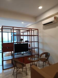a living room with a tv and a table and chairs at Timurbay Seafront Residence Mawar Inap Homestay in Kuantan