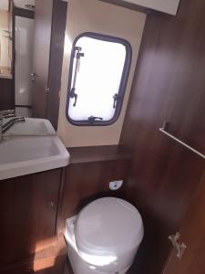 a small bathroom with a toilet and a sink at Easicampers Edinburgh in Broxburn