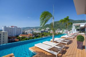 a hotel swimming pool with lounge chairs and palm trees at The Marina Phuket Hotel in Patong Beach