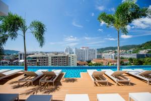 パトンビーチにあるThe Marina Phuket Hotelのヤシの木が茂るスイミングプール(ラウンジチェア付)