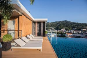 a balcony with white lounge chairs on a building at The Marina Phuket Hotel in Patong Beach