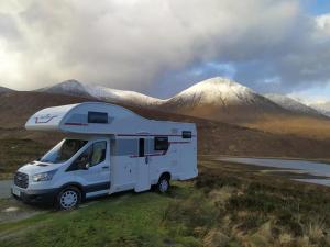 a white rv parked in front of a mountain at Easicampers Edinburgh in Broxburn