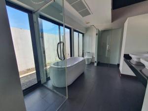 a bathroom with a bath tub and a glass wall at Blu Village Pool Villa in Bang Tao Beach