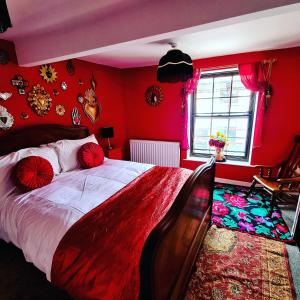 - une chambre avec un grand lit aux murs rouges dans l'établissement Frida's Cottage Whitby, à Whitby