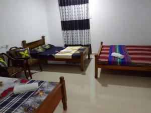 Habitación con 3 camas y sillas. en Wilpattu buma, en Nochchiyagama