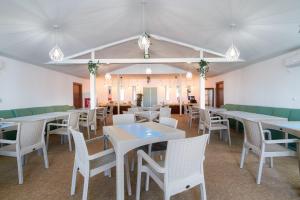 un comedor con mesas blancas y sillas blancas en Amore Resort en Băltenii de Sus