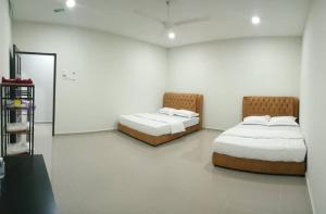 クアラ・トレンガヌにあるTAMU ROOMSTAY TOK MOLORの白い壁の客室内のベッド2台