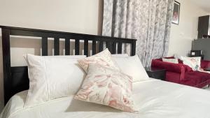 a white bed with a pink floral pillow on it at Amazing Studio near CBD in Mombasa