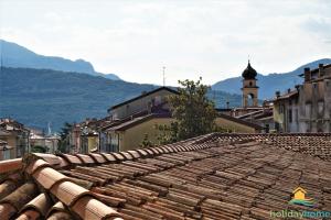 een oud tegeldak van een stad met een klokkentoren bij Lake Garda Home in Riva del Garda