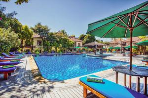 a swimming pool with lounge chairs and an umbrella at Risata Bali Resort & Spa in Kuta