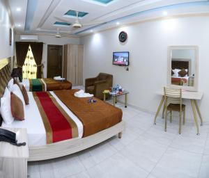 Hotel Deluxe Johar Town Lahore في لاهور: غرفة فندقية بسريرين ومكتب