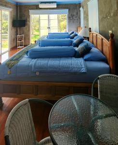 Rimtharnn Homestay Maewin في Mae Wang: سرير كبير مع وسائد زرقاء وطاولة زجاجية